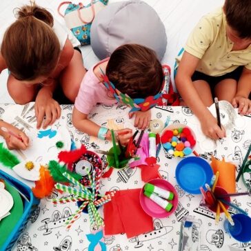 An overhead picture of children at The Kids Table doing activities such as drawing and colouring.